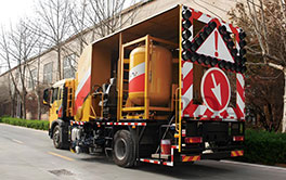 Rear view of thermoplastic road marking truck equipped with safety warning signs and arrow board