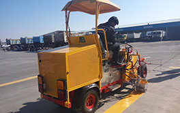 Thermoplastic road marking machine applying yellow line on asphalt pavement